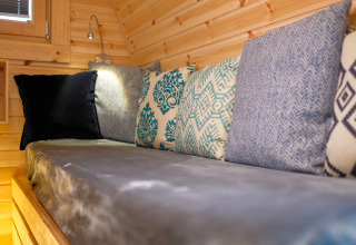 Hyggelig siddeplads med farverige puder i en træbeklædt hytte ved Natuurpark Camping Prinzenholz.