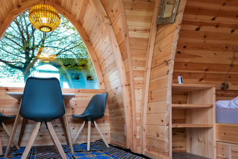 Sfeervolle glampingaccommodatie in Natuurpark Camping Prinzenholz met groot raam en houten bekleding.