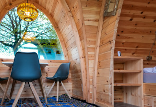 Intérieur d’un pod glamping de luxe au Natuurpark Camping Prinzenholz avec grande fenêtre et murs en bois.