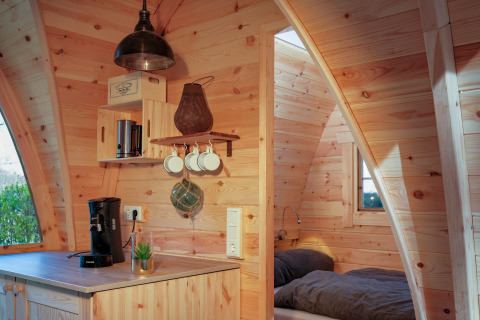 Houten interieur van een glamping accommodatie bij Natuurpark Camping Prinzenholz, met keuken en slaapplaats.