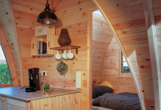 Holzinterieur einer Glamping-Unterkunft im Natuurpark Camping Prinzenholz mit Kochnische und Schlafzimmer.