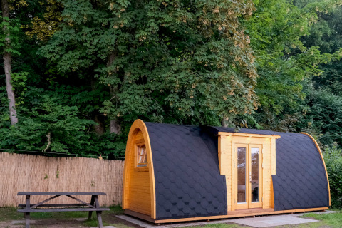 Alojamiento de glamping en Natuurpark Camping Prinzenholz, cabaña de madera rodeada de bosque verde.