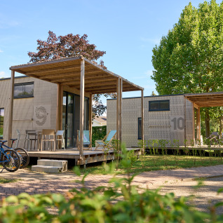 Tiny Houses på Strandcamping Podersdorf am See i Østrig med cykler og udendørs terrasse under træer.