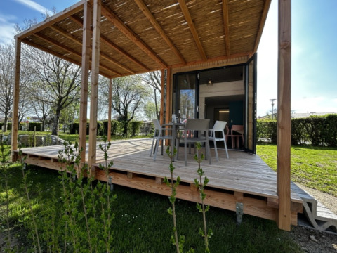 Outdoor terrace of a Strandcamping Podersdorf am See tiny house, Austria, with dining table and chairs.