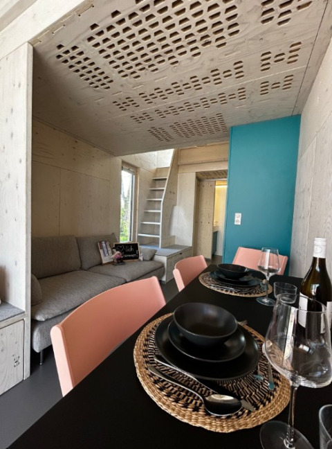 Hébergement glamping moderne en tiny house bois avec coin repas, canapé et escalier à Podersdorf am See.