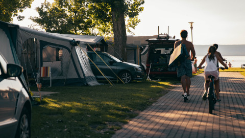 Glamping at Strandcamping Podersdorf am See with tents, campers, vehicles and families near the lakeshore.