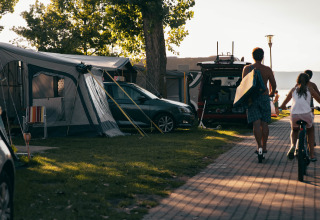 Glamping bij Strandcamping Podersdorf am See met tenten, auto's en gezinnen dicht bij het meer.