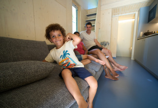 Una famiglia si rilassa in una moderna tiny house allo Strandcamping Podersdorf am See, in Austria.