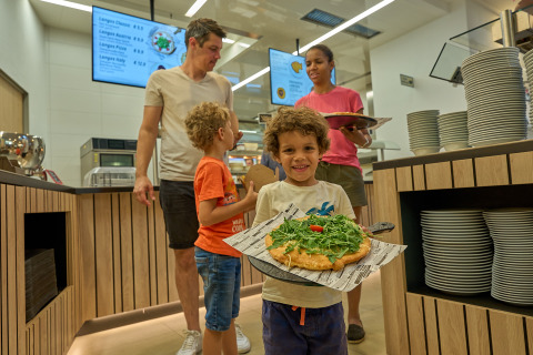 Familia disfrutando de una comida en cafetería moderna en Strandcamping Podersdorf am See - Tiny Houses, Austria.