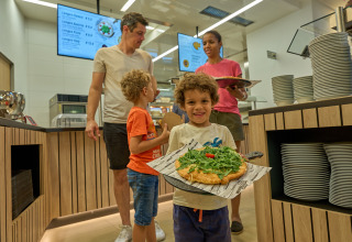 Familia disfrutando de una comida en cafetería moderna en Strandcamping Podersdorf am See - Tiny Houses, Austria.