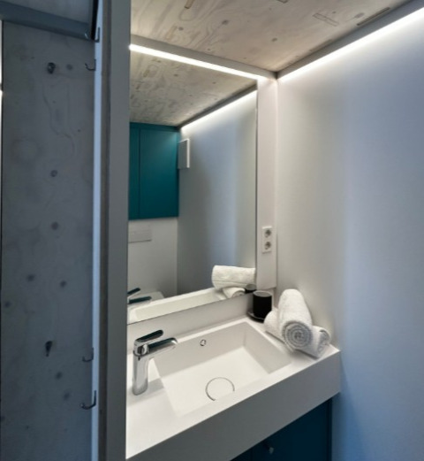 Moderno lavabo con espejo en una tiny house de Strandcamping Podersdorf am See, Austria, alojamiento glamping.