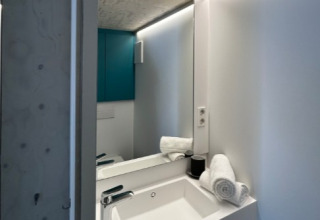 Moderne vask med spejl i et tiny house på Strandcamping Podersdorf am See, Østrig, glamping-faciliteter.