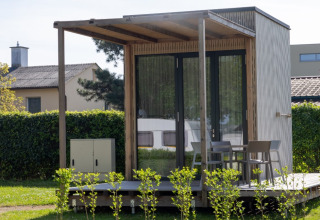 Modern tiny house glamping accommodation at Strandcamping Podersdorf am See, Austria, with deck and chairs.