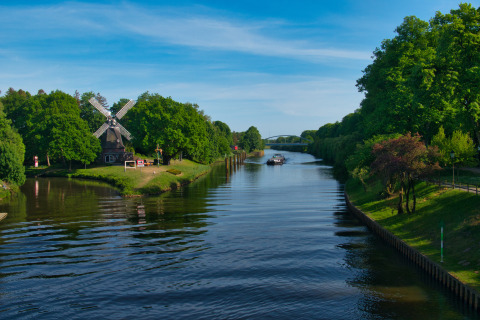Tinyhouse KLEINES EMS-IDYLL glamping en kamperen aan een rivier met molen en bomen in Emsland, Duitsland.