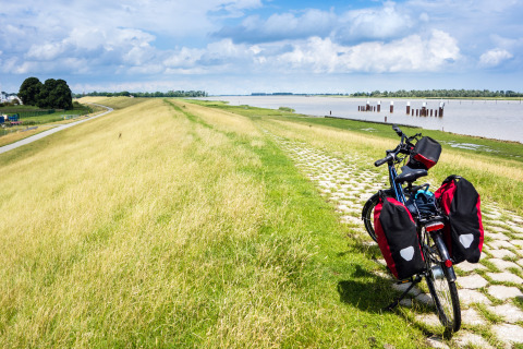 Fiets met fietstassen op rivierdijk, vlak bij Tinyhouse KLEINES EMS-IDYLL in Emsland, Duitsland, geparkeerd.