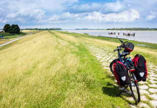 Fiets met fietstassen op rivierdijk, vlak bij Tinyhouse KLEINES EMS-IDYLL in Emsland, Duitsland, geparkeerd.