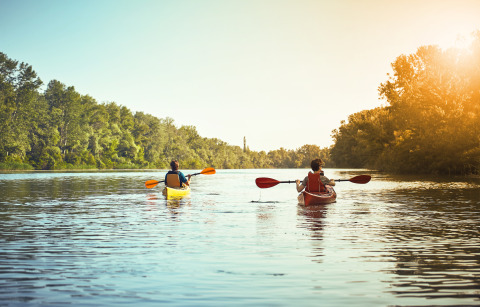 Due persone in kayak pagaiando su un fiume tranquillo vicino al glamping Tinyhouse KLEINES EMS-IDYLL a Emsland.