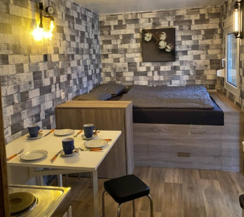 Hébergement glamping tinyhouse moderne avec lit, coin repas et kitchenette près du Heegermeer en Allemagne.