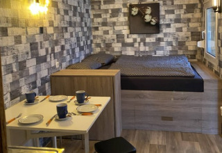 Moderne tinyhouse-indkvartering med seng, spisebord og køkken i hyggelig campingstil ved Heegermeer.