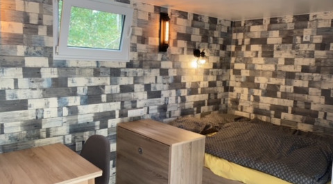 Innenraum eines Tinyhouses mit Bett, Fenster und Schreibtisch bei Kanoboerderij aan het Heegermeer in Mecklenburg-Vorpommern.