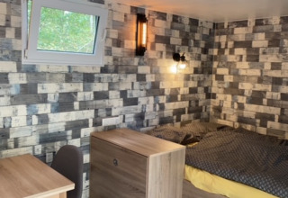 Interior de una tinyhouse con cama, ventana y escritorio en Kanoboerderij aan het Heegermeer en Mecklenburg-Vorpommern.