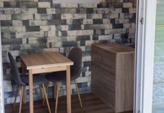 Indvendig visning af en lille stue med spisebord, stole og træpaneler i et glamping tinyhouse i Mecklenburg-Vorpommern.