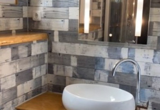 Bagno moderno in tinyhouse con piano in legno, lavabo e specchio, glamping all’Heegermeer, Meclemburgo-Pomerania.