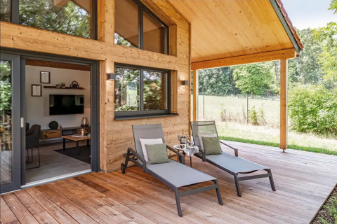 Terraza de madera con tumbonas en el glamping de lujo Vital CAMP Bayerbach en Baviera, Alemania.