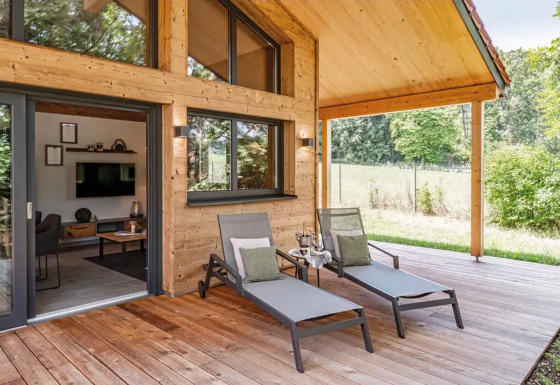 Terraza de madera con tumbonas en el glamping de lujo Vital CAMP Bayerbach en Baviera, Alemania.