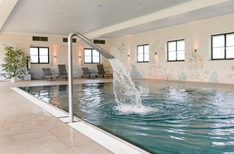 Indoor pool with waterfall feature and loungers at Vital CAMP Bayerbach - Luxe stacaravans Beieren.