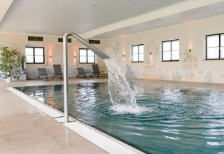 Indendørs pool med vandfaldsfunktion og liggestole på Vital CAMP Bayerbach - Luxe stacaravans Beieren.