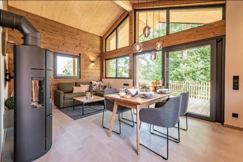 Intérieur d'un hébergement glamping de luxe Vital CAMP Bayerbach avec murs en bois, grandes fenêtres et mobilier moderne.