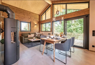 Interieur van luxe glampingaccommodatie bij Vital CAMP Bayerbach met houten wanden, grote ramen en modern meubilair.