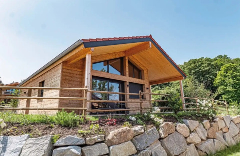 Alojamiento glamping de madera en Vital CAMP Bayerbach, con terraza de piedra y entorno verde y soleado.