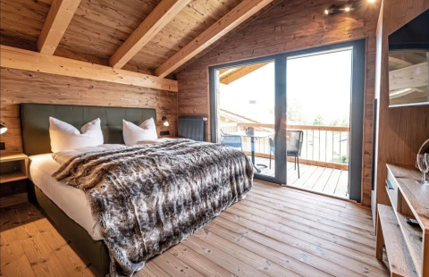 Dormitorio glamping de lujo con interior de madera y gran balcón en Vital CAMP Bayerbach, Baviera.
