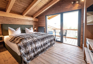 Dormitorio glamping de lujo con interior de madera y gran balcón en Vital CAMP Bayerbach, Baviera.