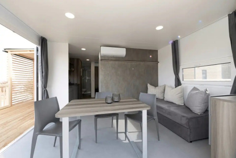 Alloggio glamping moderno con tavolo da pranzo e divano presso Vital CAMP Bayerbach, casa mobile di lusso.