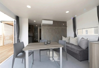 Alojamiento glamping moderno con mesa de comedor y sofá en Vital CAMP Bayerbach, casa móvil lujosa.