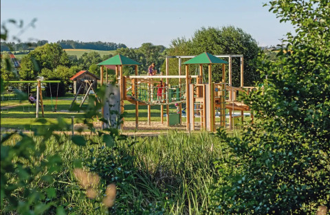Aire de jeux entourée de verdure au Vital CAMP Bayerbach, glamping avec lodges de luxe en Bavière.