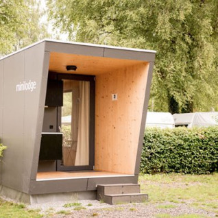 Moderne Mini-Lodge Unterkunft im Campingpark Gohren, Baden-Württemberg, umgeben von grünem Laub.