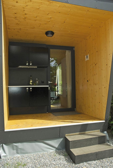 Mini lodge moderna en Campingpark Gohren, Baden-Württemberg, con terraza de madera y cocina compacta.