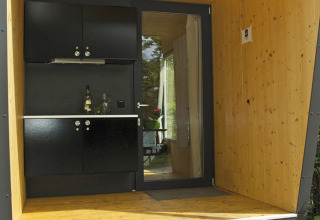 Mini lodge moderna en Campingpark Gohren, Baden-Württemberg, con terraza de madera y cocina compacta.