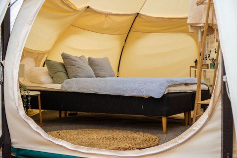 Innenansicht eines luxuriösen Glampingzeltes im Marsk Camp Dänemark mit bequemen Bett und Dekoration.