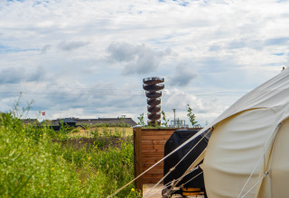 Glamping telt og en unik spiraludsigtsplatform på Marsk Camp, omgivet af grønne marker i Danmark.