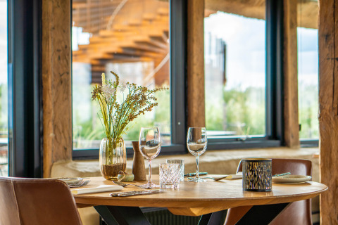 Table élégamment dressée avec fleurs dans une tente glamping à Marsk Camp, Danemark, vue sur la nature.