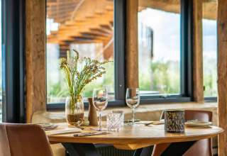 Stylishly set table with flowers inside a glamping tent at Marsk Camp, Denmark, with scenic window views.
