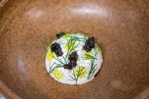Gourmet dish with caviar, herbs, and sauce in a rustic bowl at Marsk Camp - Glampingtenten Denmark camping site.