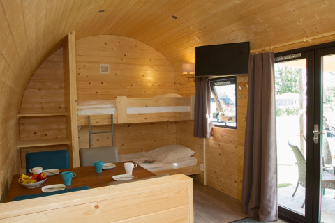 Interieur van een glamping pod bij Nordsee Camp-Norddeich met stapelbedden, eethoek en houten wanden.