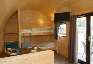 Interieur van een glamping pod bij Nordsee Camp-Norddeich met stapelbedden, eethoek en houten wanden.