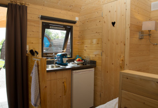 Modern glamping pod at Nordsee Camp-Norddeich featuring a compact kitchenette, wood walls, and cozy vibe.